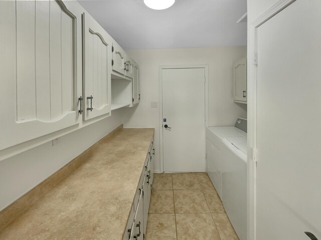 clothes washing area with light tile patterned flooring, cabinets, and washer and clothes dryer