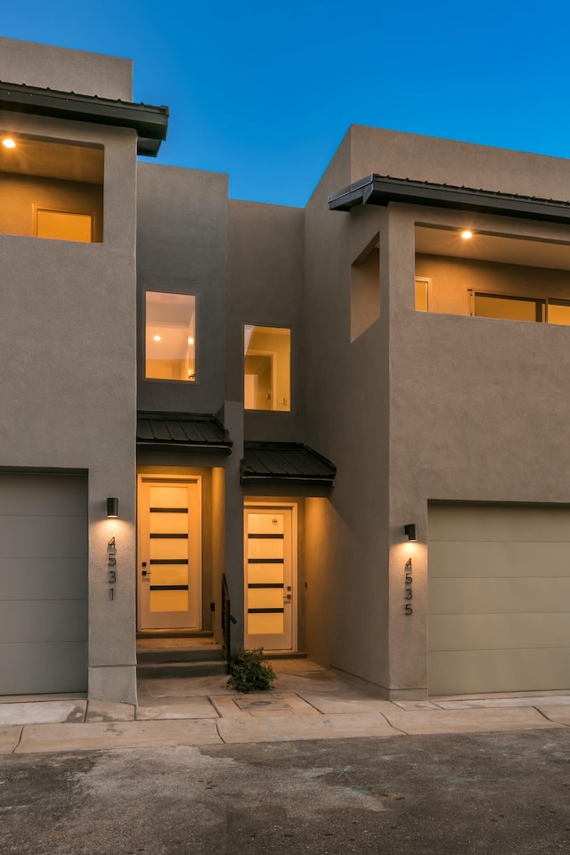 view of front of home with a garage, a standing seam roof, metal roof, and stucco siding