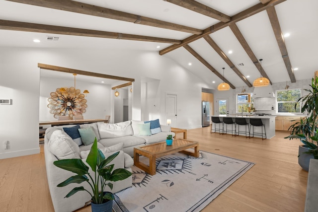 living area with light wood-style floors, visible vents, high vaulted ceiling, and beamed ceiling