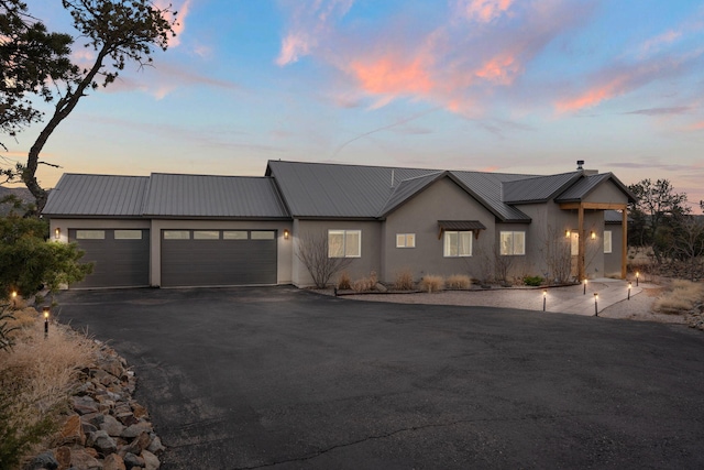 modern inspired farmhouse with a garage, metal roof, driveway, and stucco siding