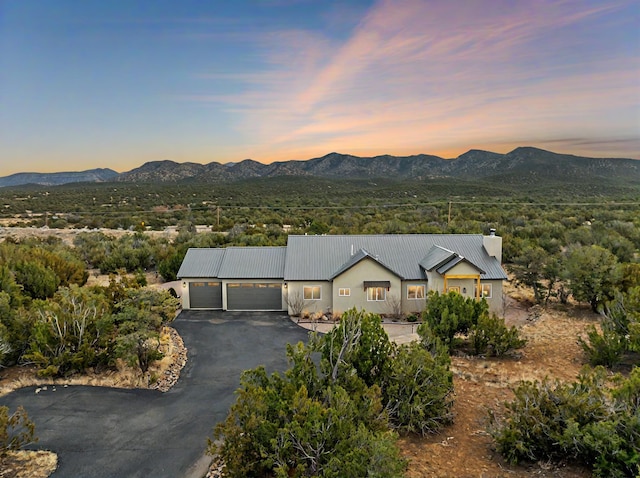 view of front of property with a garage, metal roof, a mountain view, and aphalt driveway