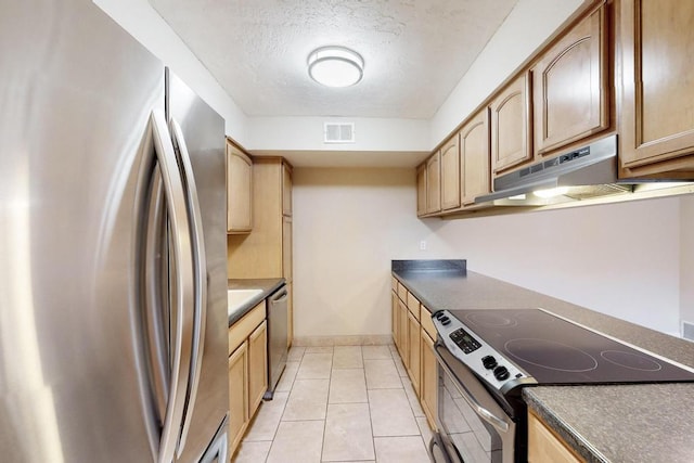 kitchen with light tile patterned flooring, stainless steel appliances, and a textured ceiling