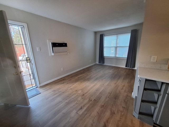 unfurnished living room featuring hardwood / wood-style flooring, a healthy amount of sunlight, and a wall mounted air conditioner