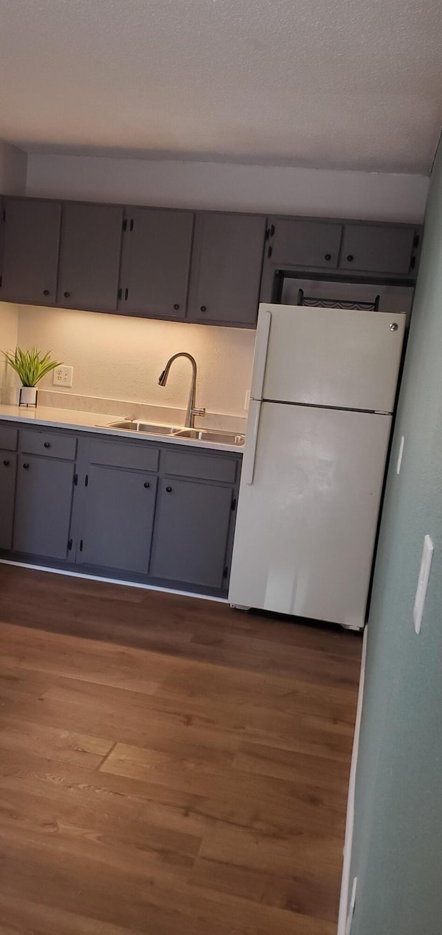 kitchen featuring sink, gray cabinets, dark hardwood / wood-style floors, white refrigerator, and a textured ceiling