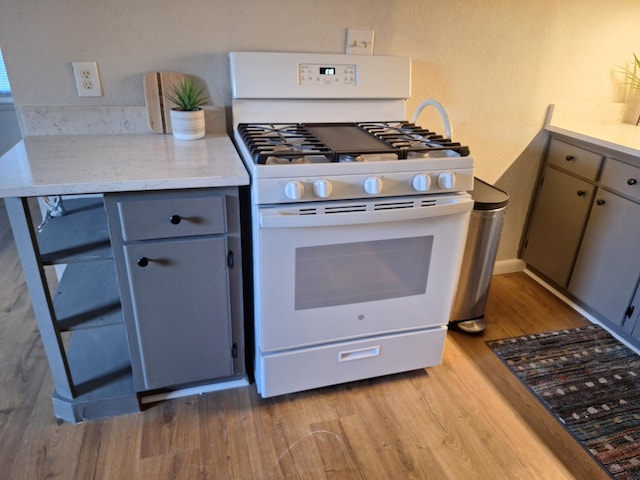 kitchen with gray cabinets, light hardwood / wood-style floors, and white range with gas stovetop