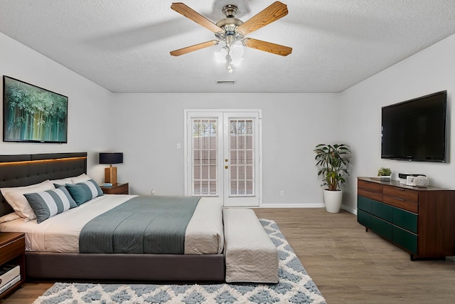 bedroom featuring light wood finished floors, visible vents, a textured ceiling, and french doors