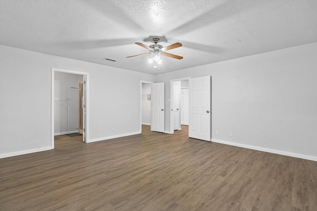 unfurnished bedroom featuring a walk in closet, visible vents, baseboards, and wood finished floors