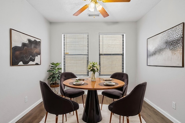 dining area with baseboards, wood finished floors, visible vents, and a healthy amount of sunlight