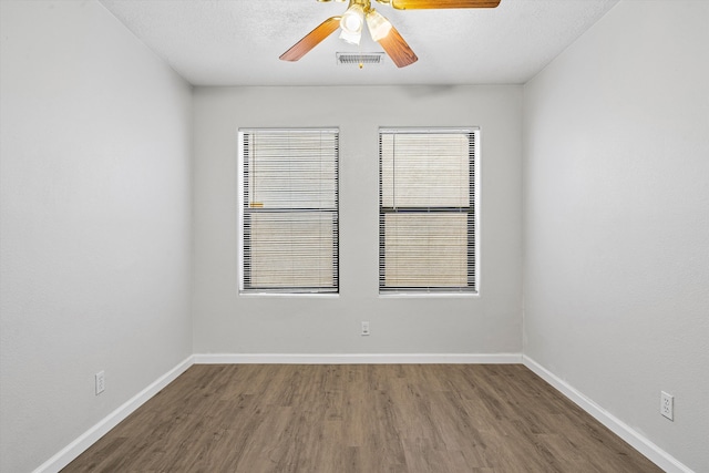 spare room with baseboards, wood finished floors, visible vents, and a healthy amount of sunlight