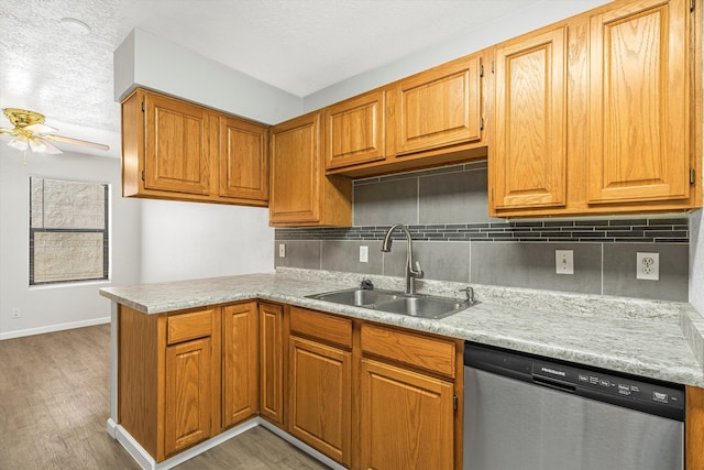 kitchen featuring light wood-style flooring, backsplash, stainless steel dishwasher, a sink, and a peninsula