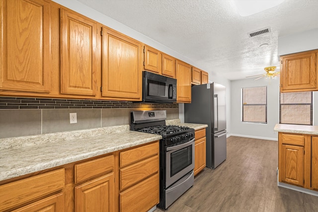 kitchen featuring appliances with stainless steel finishes, dark wood-style flooring, light countertops, and a ceiling fan