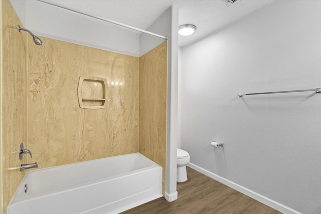 bathroom featuring toilet, washtub / shower combination, a textured ceiling, wood finished floors, and baseboards