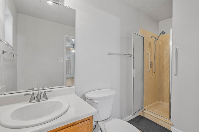 bathroom featuring toilet, a stall shower, a textured ceiling, and vanity