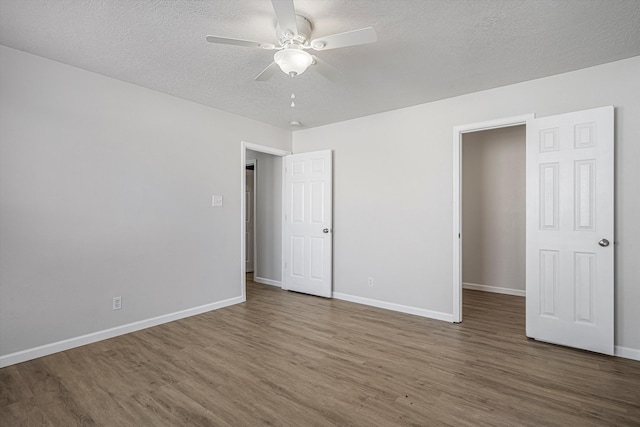 unfurnished bedroom featuring ceiling fan, a textured ceiling, baseboards, and wood finished floors