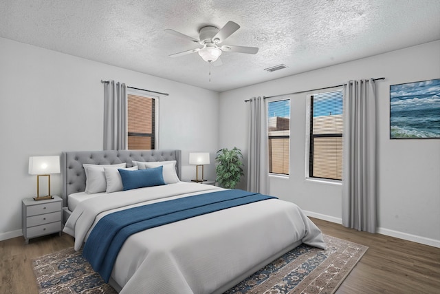 bedroom featuring a ceiling fan, wood finished floors, visible vents, and baseboards