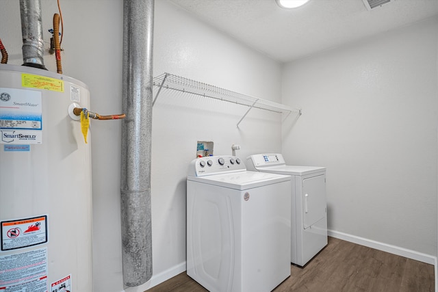 laundry area with laundry area, wood finished floors, baseboards, water heater, and washer and clothes dryer