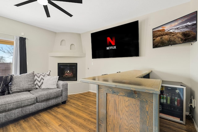 living room with ceiling fan, a large fireplace, wine cooler, and dark hardwood / wood-style flooring