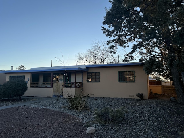 view of front of home featuring crawl space, fence, and stucco siding