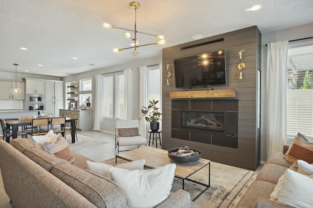 living room with a chandelier, a large fireplace, and a textured ceiling