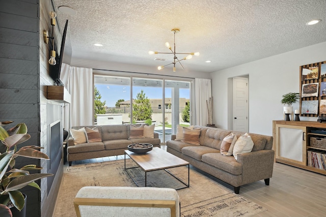 living room featuring a chandelier, light hardwood / wood-style flooring, and a textured ceiling