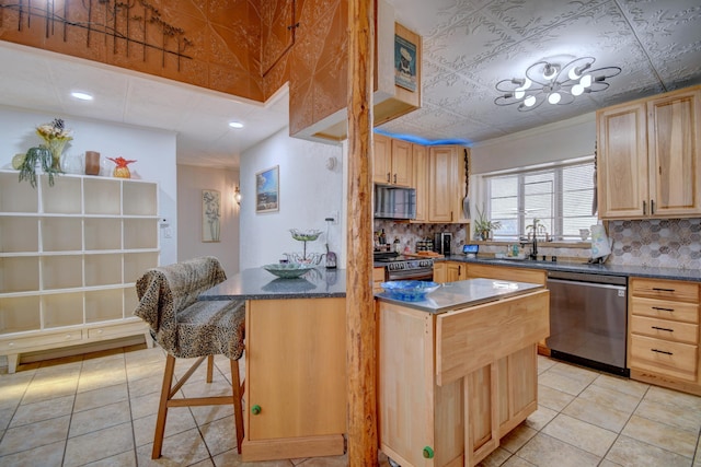 kitchen featuring stainless steel appliances, sink, a breakfast bar, and light brown cabinets