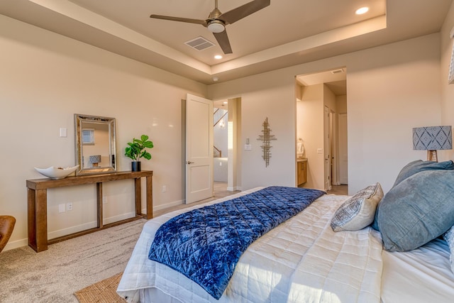 carpeted bedroom with ensuite bath and a raised ceiling