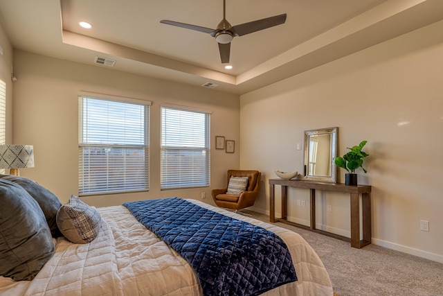 carpeted bedroom featuring a tray ceiling and ceiling fan