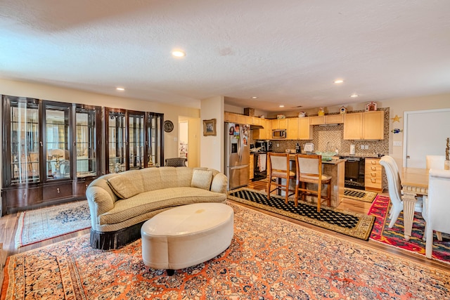 living area featuring recessed lighting, light wood-style flooring, and a textured ceiling