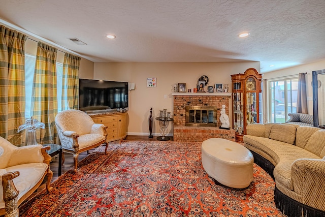 living room with recessed lighting, a brick fireplace, a textured ceiling, wood finished floors, and baseboards