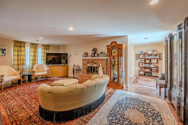 living area with a textured ceiling, a fireplace, wood finished floors, and recessed lighting