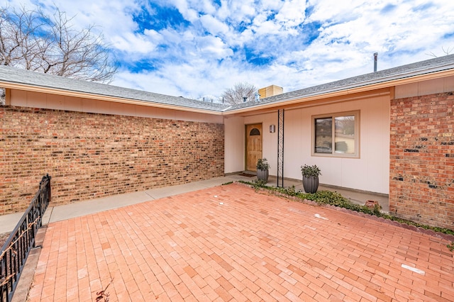 property entrance featuring a patio area and brick siding