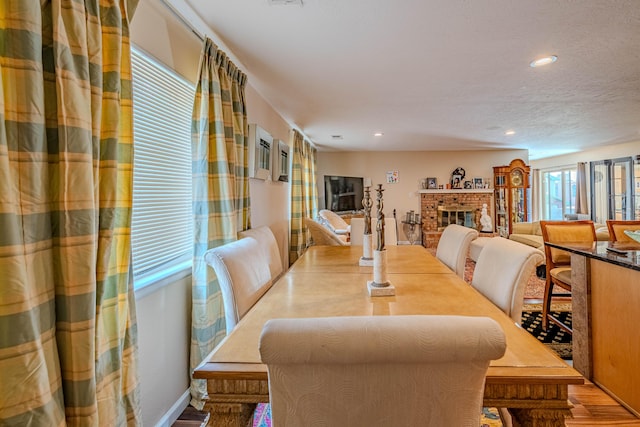 dining room with a brick fireplace, wood finished floors, and recessed lighting