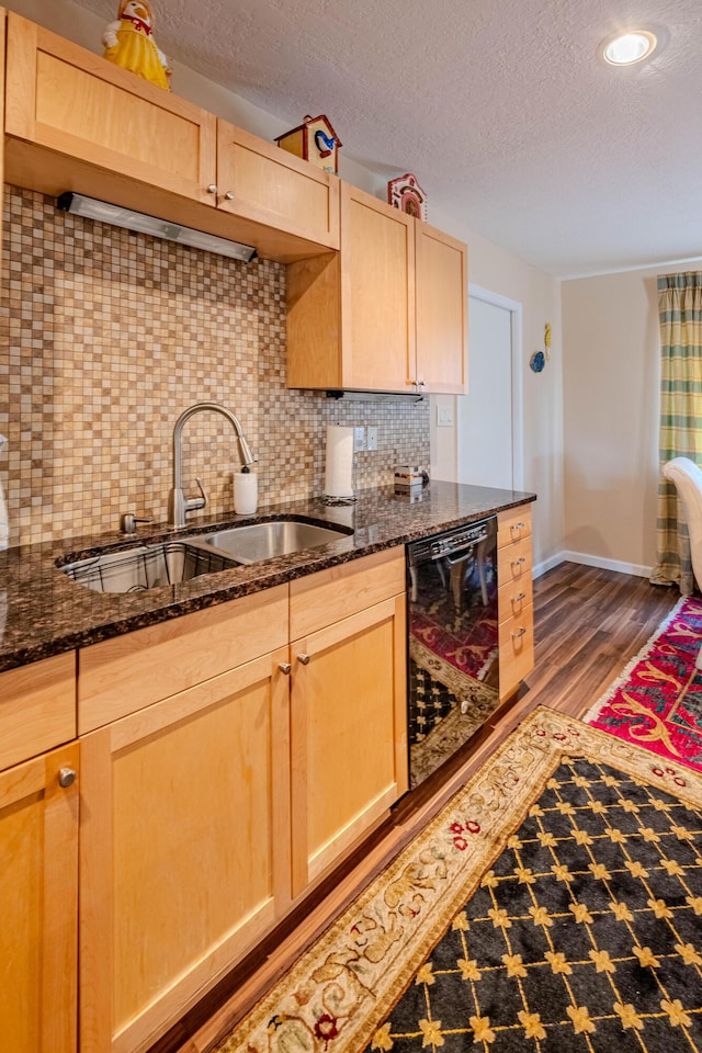 kitchen with black dishwasher, light brown cabinets, and dark stone counters