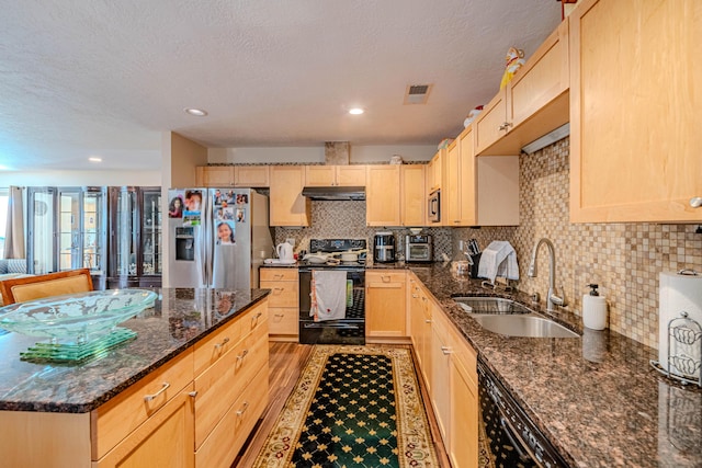 kitchen featuring dark stone counters, light brown cabinets, a sink, and black appliances