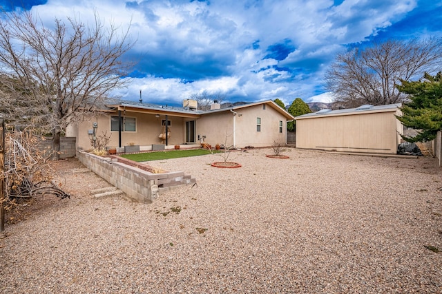 rear view of house featuring fence and stucco siding