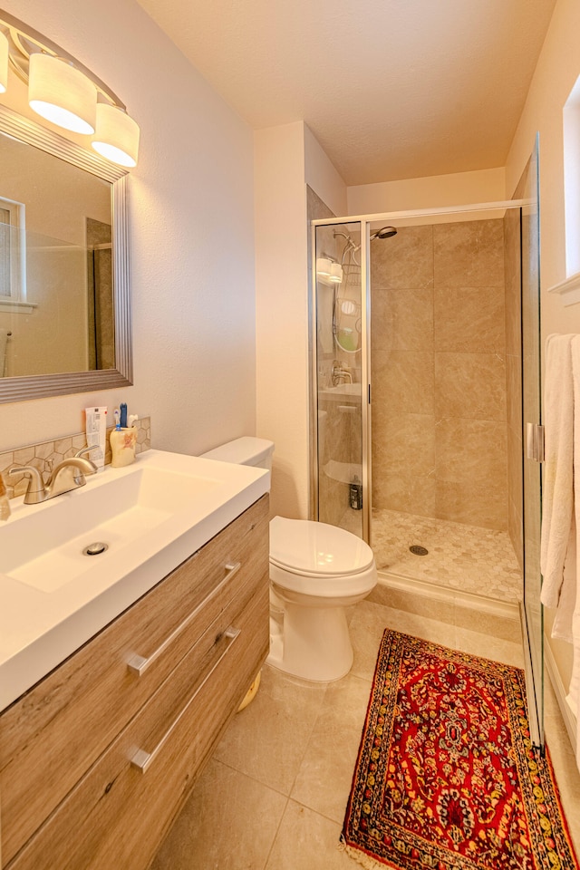 bathroom featuring a stall shower, vanity, toilet, and tile patterned floors