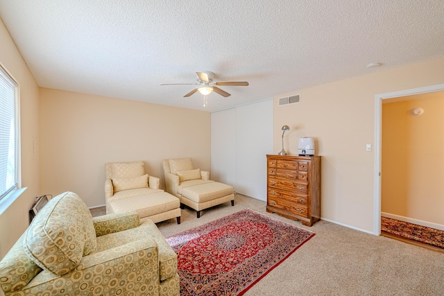 living room with carpet, a textured ceiling, visible vents, and a wealth of natural light