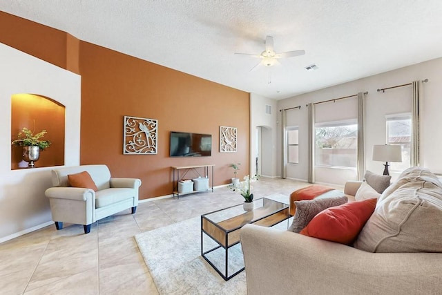 tiled living area with visible vents, ceiling fan, a textured ceiling, and baseboards