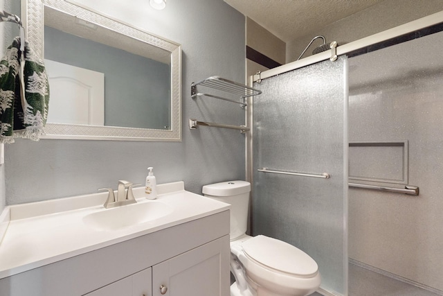 bathroom featuring vanity, toilet, a textured ceiling, and a shower with shower door