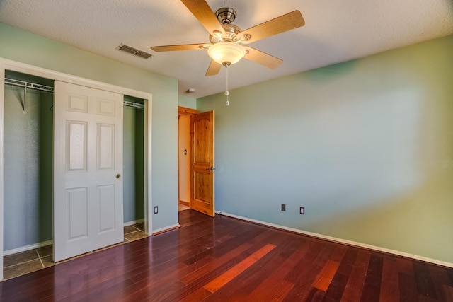 unfurnished bedroom featuring dark wood-type flooring, a closet, and ceiling fan