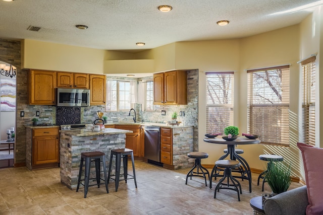 kitchen featuring a kitchen island, tasteful backsplash, sink, a breakfast bar area, and stainless steel appliances