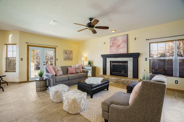 living room featuring a fireplace, a wealth of natural light, french doors, and a textured ceiling