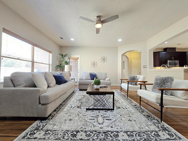 living room featuring arched walkways, a textured ceiling, recessed lighting, wood finished floors, and visible vents