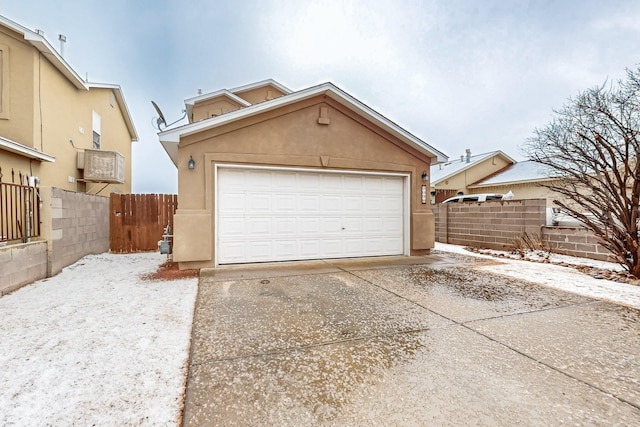 exterior space with a garage, fence, and stucco siding