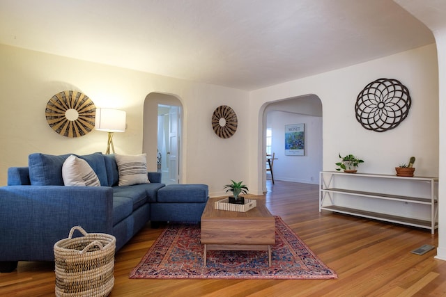 living room with visible vents, wood finished floors, and arched walkways