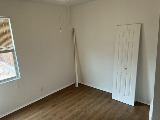 unfurnished bedroom with dark wood-style flooring and baseboards