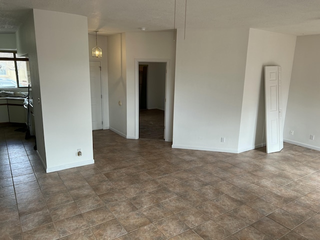 empty room featuring a textured ceiling and baseboards