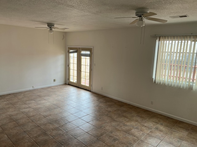 empty room with baseboards, visible vents, a ceiling fan, a textured ceiling, and french doors