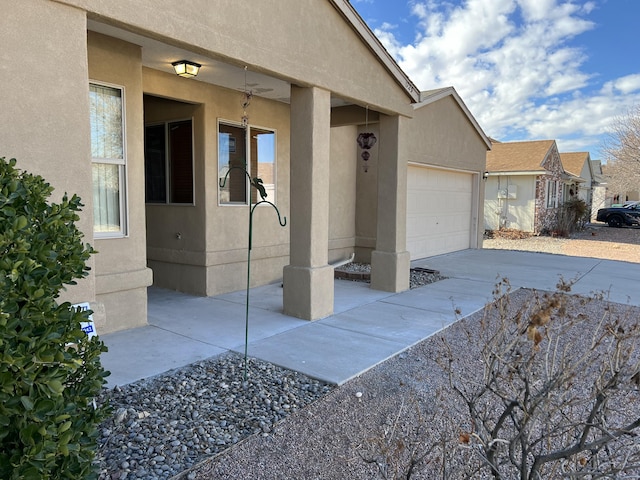 entrance to property featuring a garage, driveway, and stucco siding