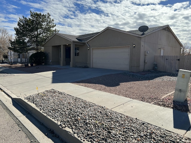 ranch-style house featuring concrete driveway, an attached garage, fence, and stucco siding